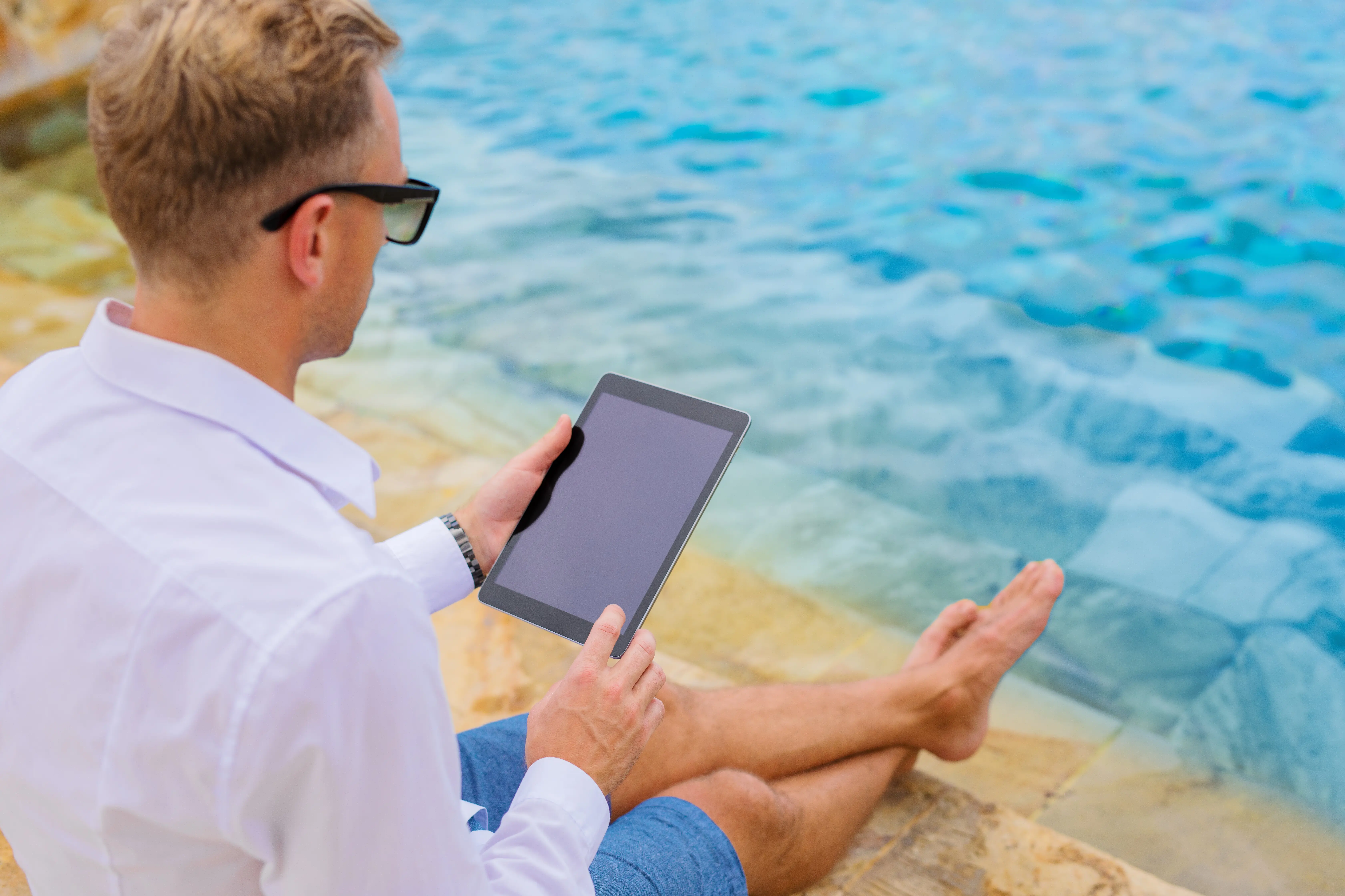 Geschäftsmann mit Tablet-Computer am Pool